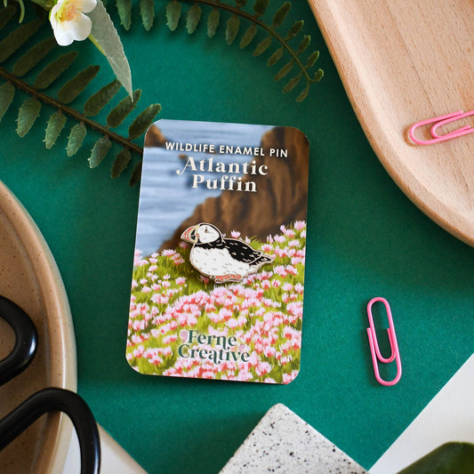 Atlantic Puffin enamel pin card on a green surface with decorative elements