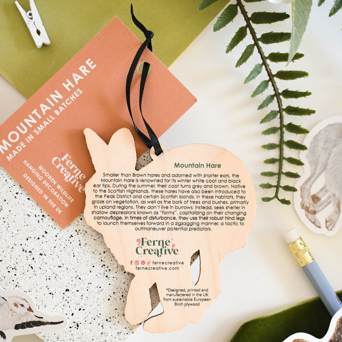 Mountain hare product with branding on a decorative surface with greenery and stationery items.