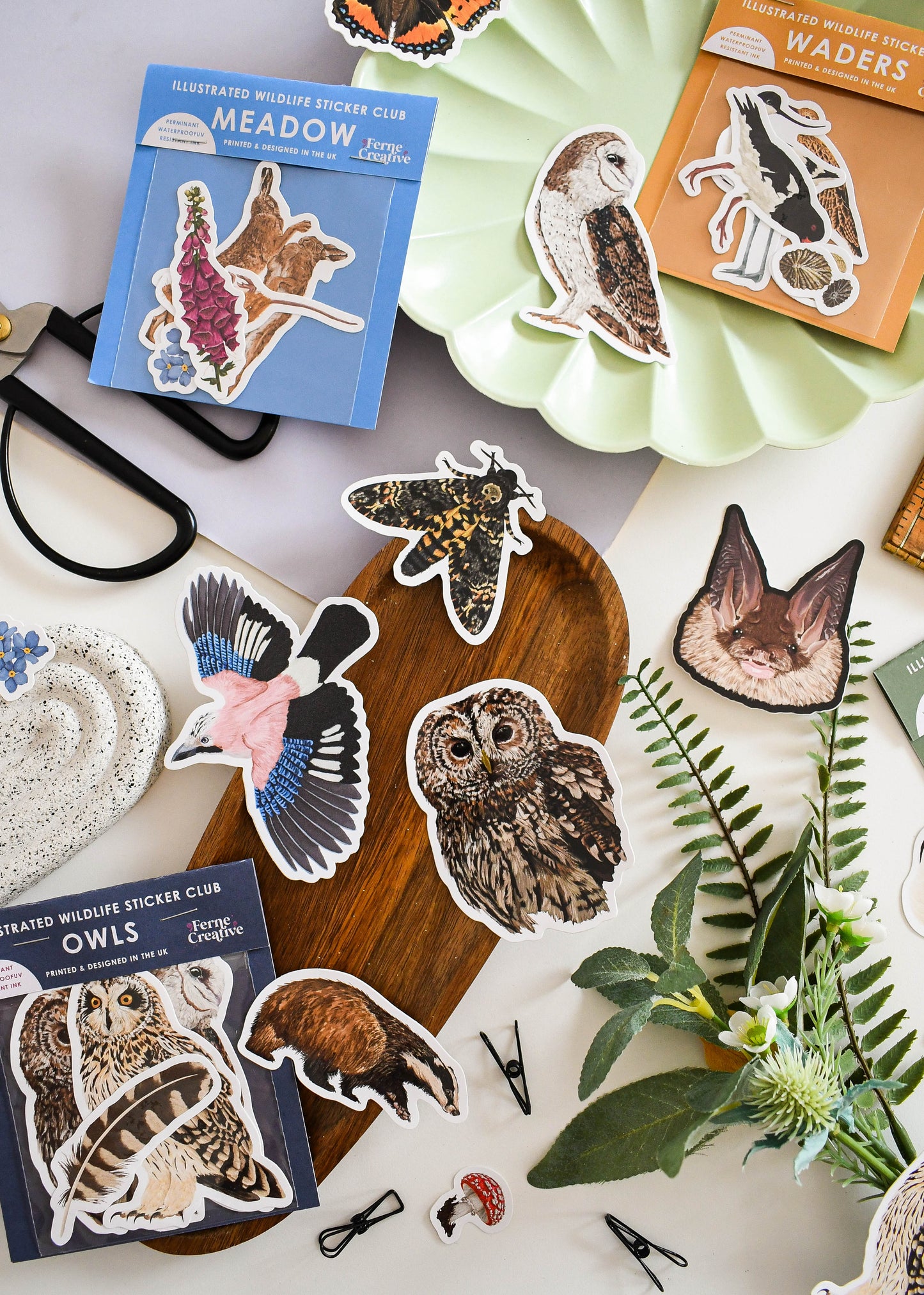 Sticker set of illustrated wildlife, including owls and other animals, on a white surface with nature-themed decor.