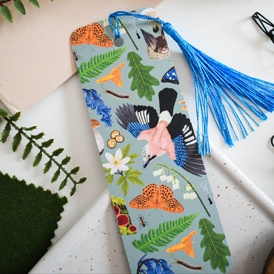 Decorative nature bookmark with tassel on a textured surface with leaves and scissors.
