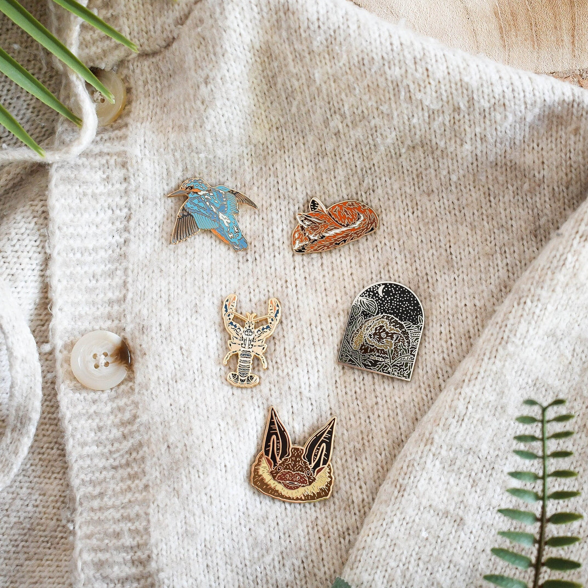 wildlife enamel pins on woven cardigan 