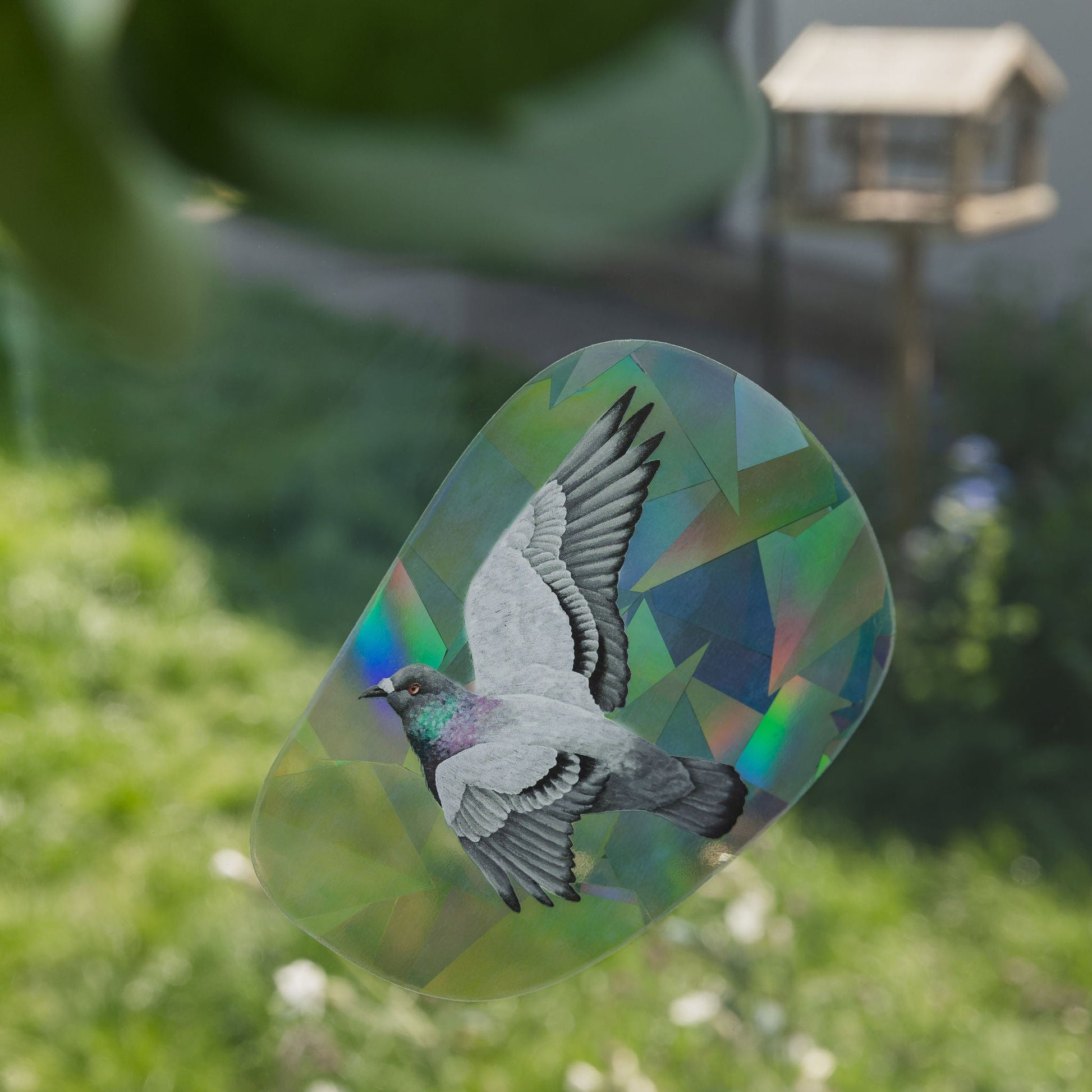 Decorative glass panel with a bird design in a garden setting