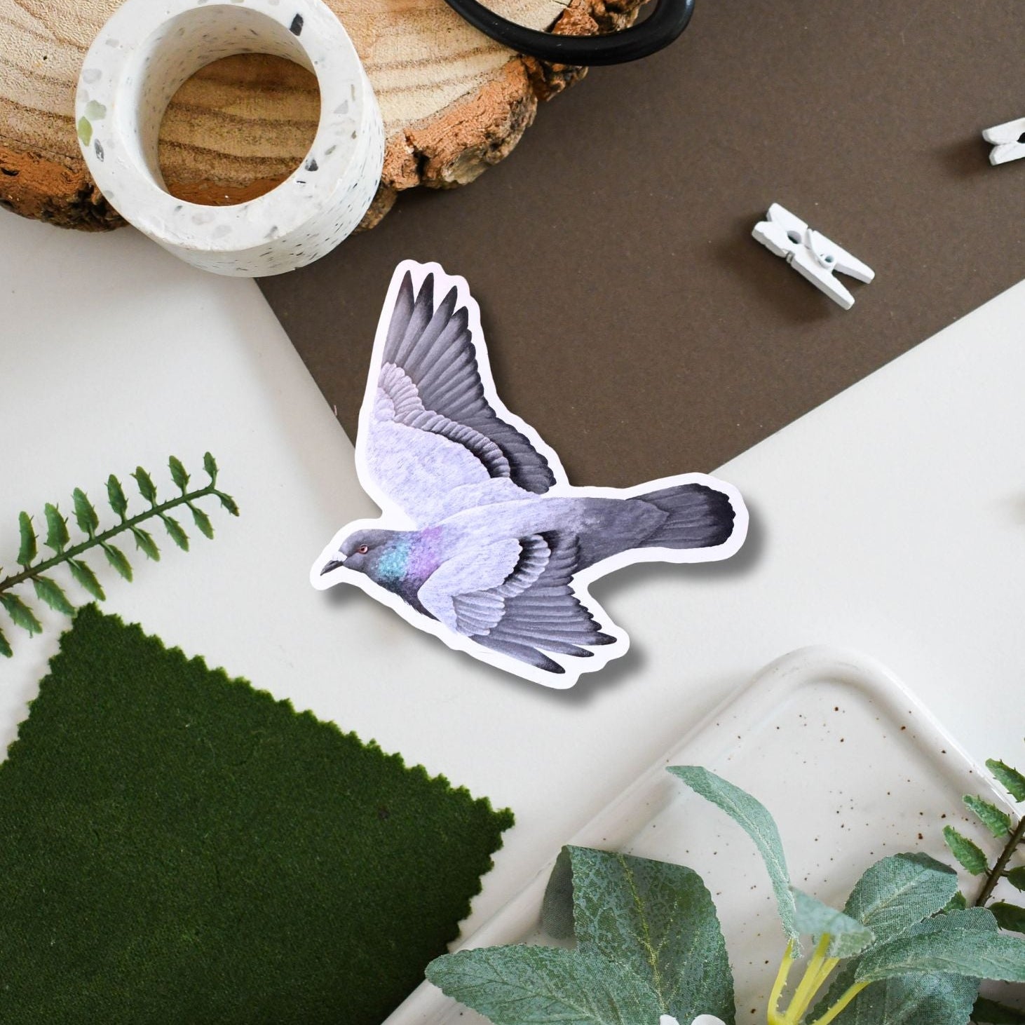 Decorative sticker of a pigeon flying on a surface with plants and a candle.