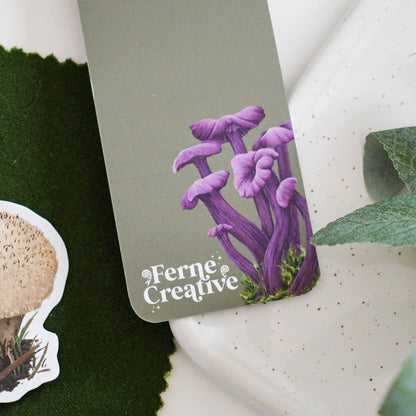 Purple mushroom illustration on a green card with 'Ferne Creative' branding, surrounded by greenery.
