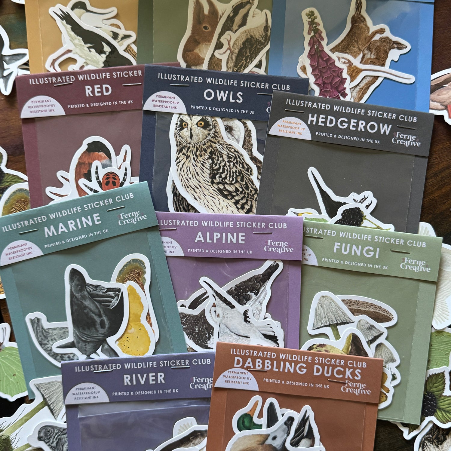 A collection of illustrated wildlife sticker clubs by Ferrie Creations, featuring various animal and nature-themed stickers on colorful cardstock packs arranged on a dark wooden surface.