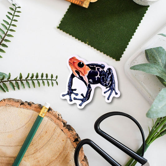 Sticker of a colorful frog on a surface with greenery and tools